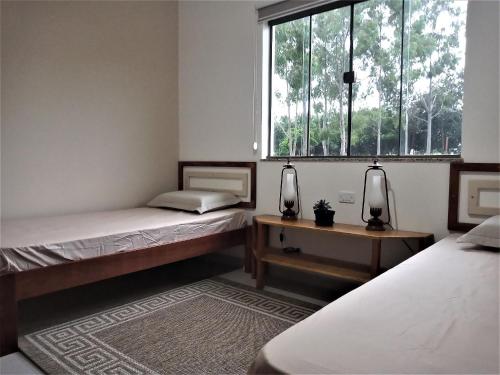 um quarto com duas camas e uma janela em Sítio São Luiz, R2: Refúgio rústico na Natureza em Quadra