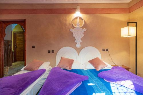 - une chambre avec un grand lit et des oreillers violets dans l'établissement Riad Tourtit, à Imlil