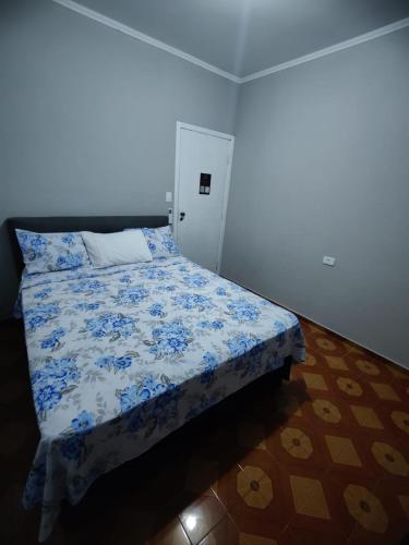 a bedroom with a bed with a blue and white comforter at Villa Fátima Hostel GRU in Guarulhos