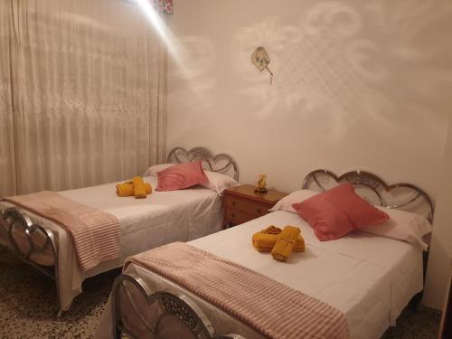 twee bedden in een kamer met gele knuffels erop bij Casa el Correo in Villanueva del Trabuco