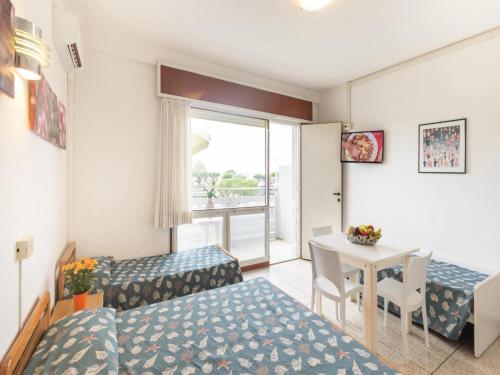 Cette chambre comprend un lit, un bureau et une table. dans l'établissement Cozy studio apartment with sea view - Beahost, à Lignano Sabbiadoro
