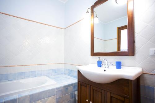 a bathroom with a sink and a mirror and a tub at Villa Pedra Moro in Alghero