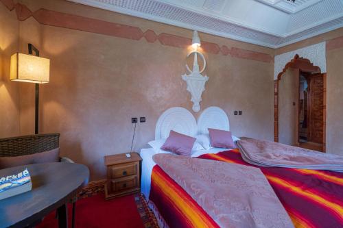 a bedroom with two beds and a table and a lamp at Riad Tourtit in Imlil