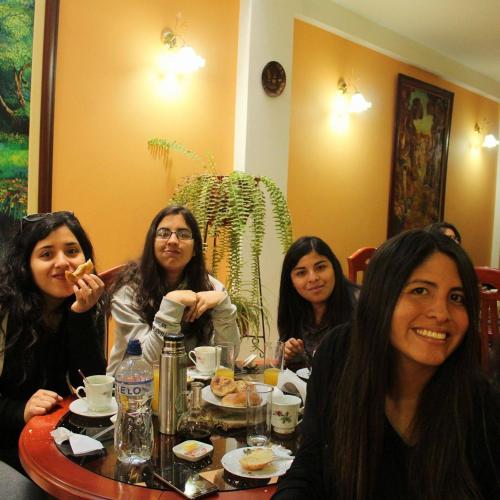 Cztery kobiety siedzące przy stole jedzące jedzenie w obiekcie Retamas Hotel EIRL w mieście Cajamarca