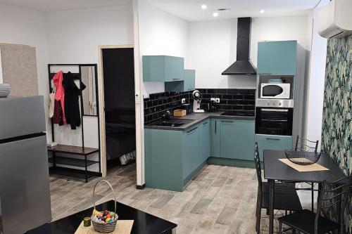 une cuisine avec des armoires bleues et une table et des chaises dans l'établissement Appartement Kantar - Le Vert D'Agate, à Anduze