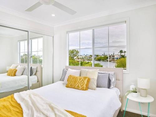 een witte slaapkamer met 2 bedden en een raam bij Broadwater Lux home in Gold Coast