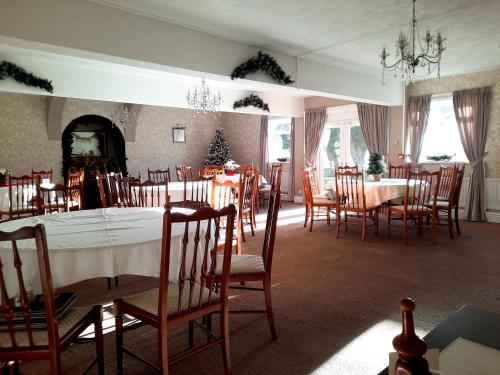 een eetkamer met tafels en stoelen en een open haard bij The White Heather Hotel in Wigton