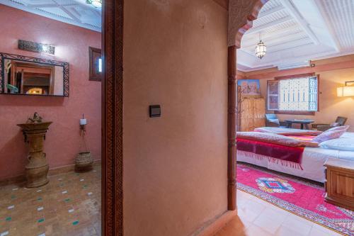 a hallway to a bedroom with two beds and a mirror at Riad Tourtit in Imlil