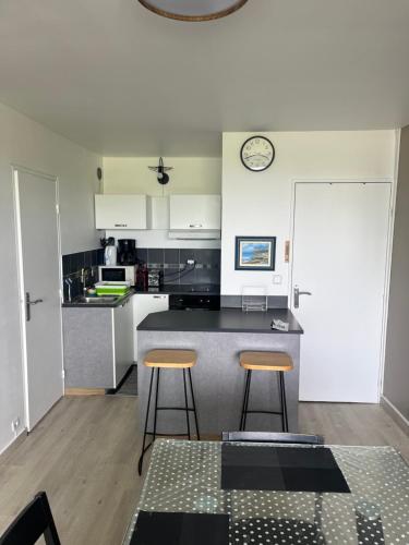 une cuisine avec un comptoir et deux tabourets de bar dans l'établissement Appartement 2 pièces à Cabourg, à Cabourg