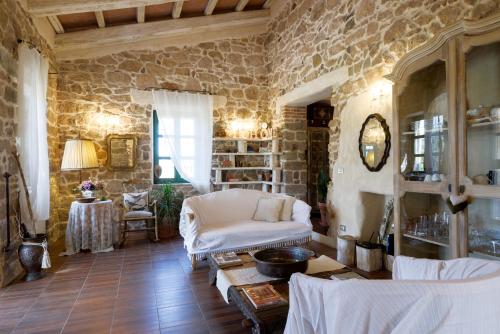 sala de estar con sofá blanco y pared de piedra en Villa in Campagna con Piscina Privata, en Uri