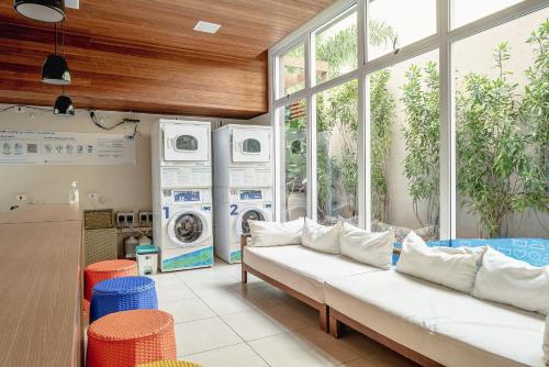 eine Waschküche mit einem weißen Sofa und Fenstern in der Unterkunft Studio com garagem, ar condicionado e piscina in São Paulo
