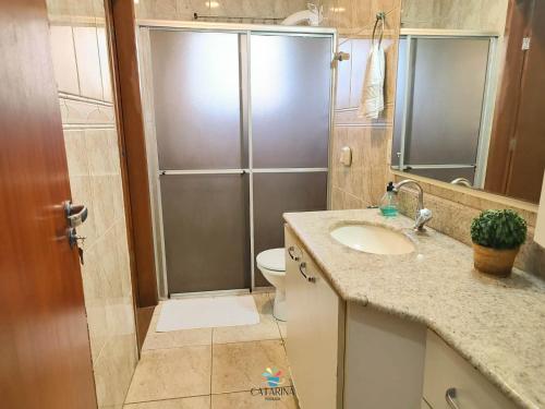 een badkamer met een douche, een wastafel en een toilet bij Pousada Catarina in Biguaçu
