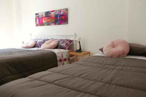 a bedroom with two beds with pink pillows on them at 4four Apartment 6-7 pax in Vitinia