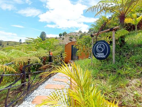 ein Schild vor einem Haus in einem Garten in der Unterkunft Glamping The Mountain in Guatapé