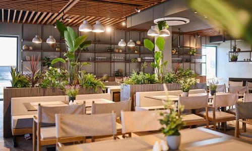 a restaurant with tables and chairs and plants at Aminess Style Glamping Villas & Holiday Homes Avalona in Povljana