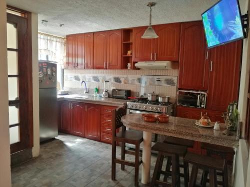 una cocina con armarios de madera y una isla de cocina con taburetes en Departamento a 10 min Terminal Quitumbe en Quito, en Quito