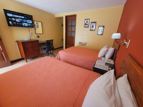 a hotel room with two beds and a desk at Hotel y Restaurante Villa Esmeralda in Quetzaltenango