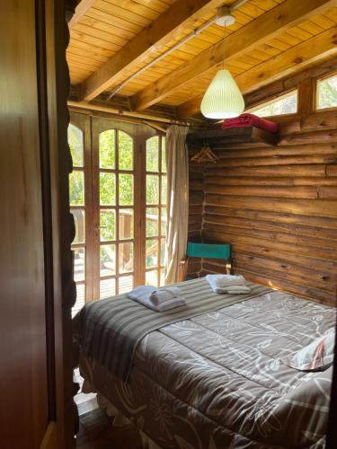 a bedroom with a bed in a log cabin at Cabaña del Río PUEBLO DEL RIO MOUNTAIN LODGE & RIO in Potrerillos