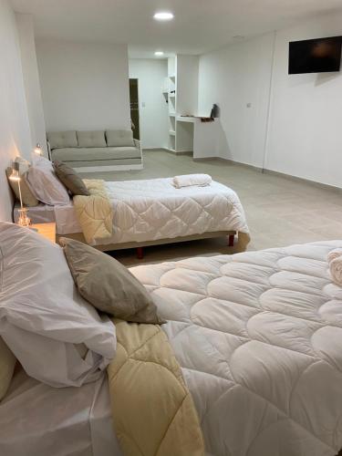 Habitación con 3 camas y sofá en GMP suites en San Miguel de Tucumán
