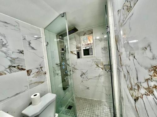 a white bathroom with a shower and a toilet at Basement Unit 25-Minute Downtown in Toronto