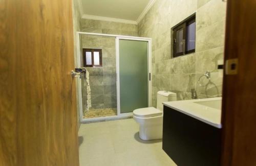 y baño con aseo, lavabo y ducha. en House of joy Bilene en Vila Praia Do Bilene
