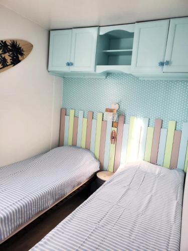 - 2 lits dans une petite chambre avec des armoires bleues dans l'établissement Les Baigneuses - Piscines chauffees, à Saint-Hilaire-de-Talmont
