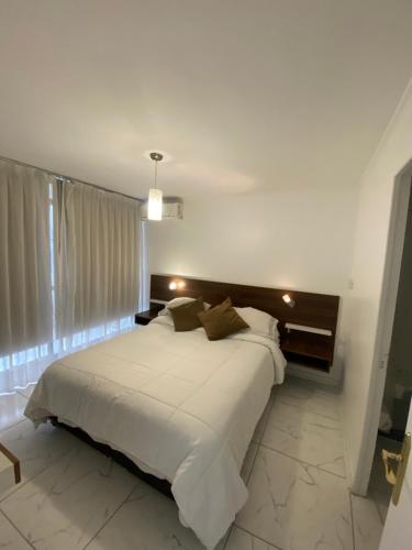 1 dormitorio con 1 cama grande con sábanas blancas en Departamento Don Miguel Claro, en Santiago