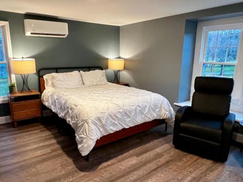 sypialnia z łóżkiem i krzesłem oraz 2 oknami w obiekcie Turner Park Suite w mieście Montour Falls