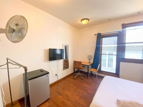 a bedroom with a bed and a desk with a fan at ITH San Diego Adventure Hostel in San Diego