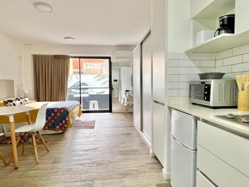a kitchen and living room with a table and a microwave at Cozy & sunny studio in Saavedra in Buenos Aires