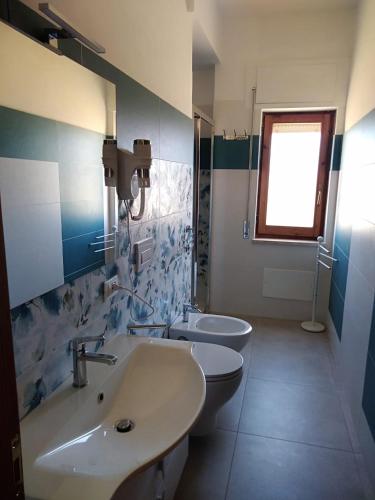 a bathroom with two sinks and a toilet and a window at Antares B&B in Cariati