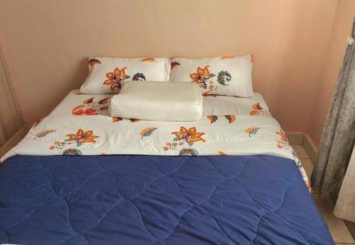 a bed with a blue and white comforter and pillows at Ecohome 5 wilderness within sight of the Airport in Nairobi