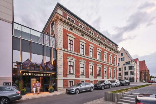 un grand bâtiment en briques avec des voitures garées devant lui dans l'établissement Hotel Anklamer Hof, BW Signature Collection, à Anklam