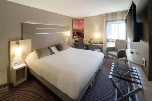 Habitación de hotel con cama blanca grande y escritorio. en Best Western Voiron Centre, en Voiron