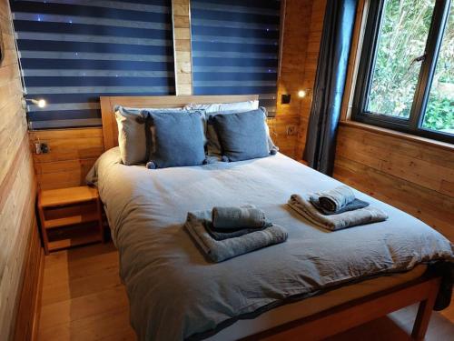 a bedroom with a large bed with towels on it at Cosy Cornish Cabin in St Austell