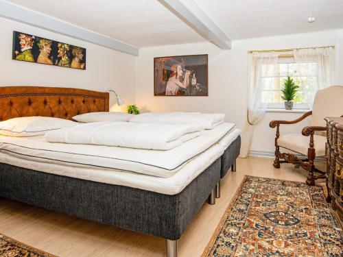 ein Schlafzimmer mit einem großen Bett und einem Stuhl in der Unterkunft Holiday home Skærbæk in Skærbæk