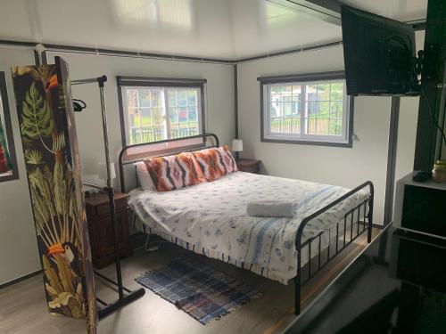ein Schlafzimmer mit einem Bett und zwei Fenstern in der Unterkunft Blue Sapphire Village Pet Friendly in Glen Innes