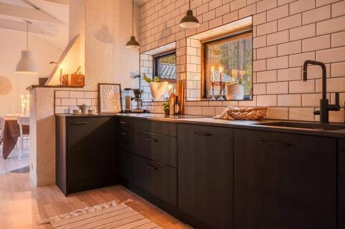 a kitchen with black cabinets and a sink and a window at Swedish Costal Forest Hideaway in Yngsjö