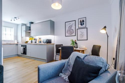 a living room with a blue couch and a kitchen at NEW! Stylish 1-Bed Flat in Crewe by 53 Degrees Property - Ideal for Business & Professionals - Sleeps 3! in Crewe