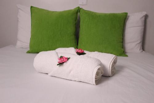 duas toalhas numa cama com almofadas verdes e flores em Pousada Casa Mar Pajuçara em Maceió