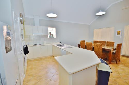 a white kitchen with a table and a dining room at Kalbarri Getaway - Kalbarri WA in Kalbarri