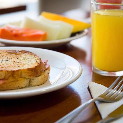 uma sanduíche num prato ao lado de um copo de sumo de laranja em Pousada Casa Mar Pajuçara em Maceió
