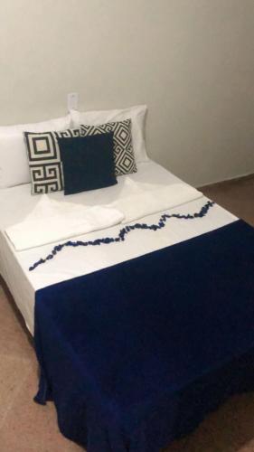 uma cama com um cobertor e almofadas azuis e brancas em Pousada Casa Mar Pajuçara em Maceió