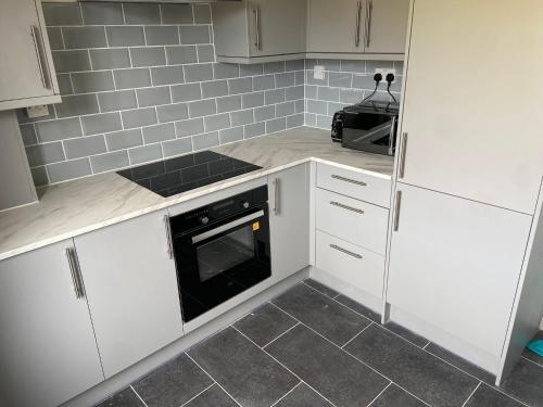 a kitchen with white cabinets and a black oven at Peeams abode in Dagenham