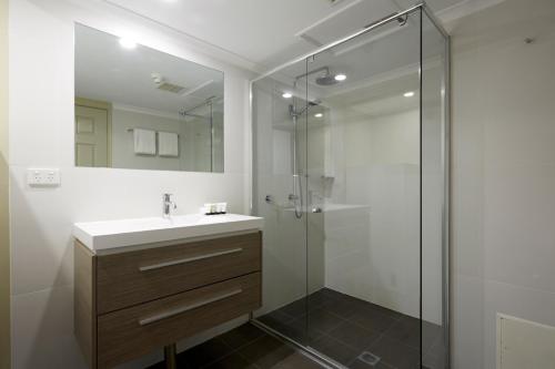 La salle de bains est pourvue d'un lavabo et d'une douche. dans l'établissement Pinnacle Apartments, à Canberra