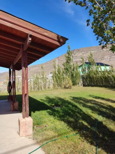 a wooden pavilion in a field with a building in the background at Azucena1001 in El Calafate