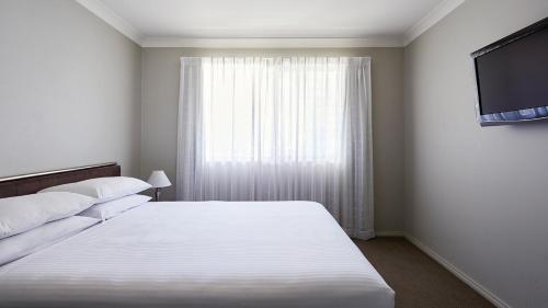 a bedroom with a white bed and a window at Pinnacle Apartments in Canberra