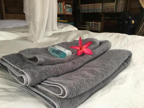 ein graues Handtuch mit einer Blume auf dem Bett. in der Unterkunft สวนบ้านนอก SuanBaanNoak in Phayao