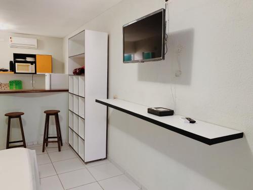 a kitchen with a counter with a tv on the wall at Flats e Suítes Elcaline in Porto De Galinhas