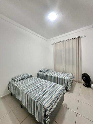- 2 lits dans une chambre aux murs blancs dans l'établissement Lazer em Salvador, à Cajiru